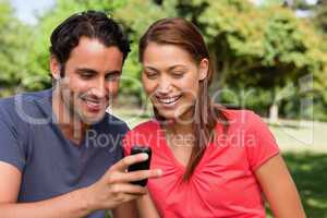 Two friends smiling as they are looking at something on a mobile