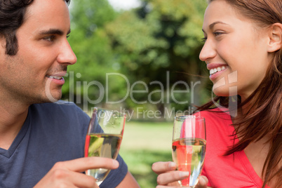 Close-up of two friends looking at each while holding glasses of