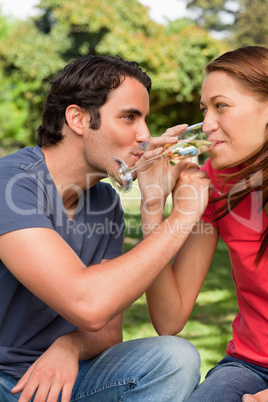 Two friends smiling as they link their arms together while drink