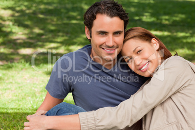 Man smiling as his friend rests his rests her head on his should