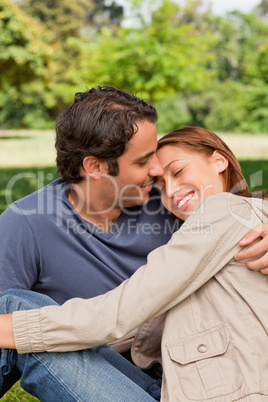 Man smiling as his friend rests her head on his shoulders