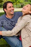 Two friends enthusiastically laughing as they are sitting next t