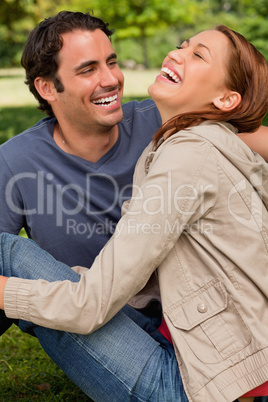Two friends gleefully laughing as they are sitting next to each