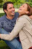 Two friends gleefully laughing as they are sitting next to each