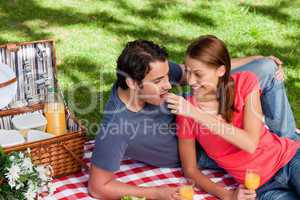 Young woman feeding her friend as they as they lie on a blanket