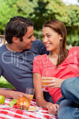 Two friends smiling  each other while they hold glasses as they