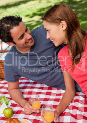 Close-up of two smiling friends lying on a blanket with a picnic
