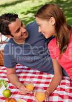 Close-up of two smiling friends lying on a blanket with a picnic
