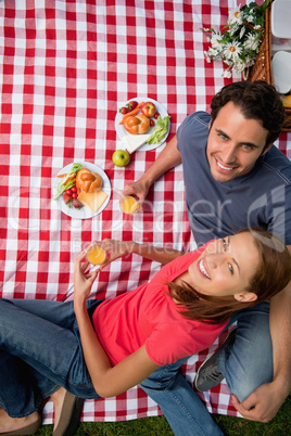 Elevated view of two smiling friends as they lie on a blanket wi