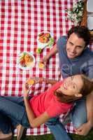 Elevated view of two smiling friends as they lie on a blanket wi