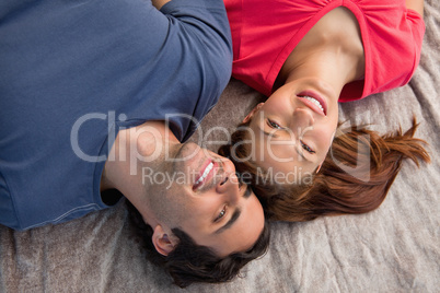 Two friends looking into the sky while lying on a quilt