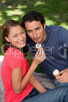 Two smiling friends looking upwards while holding ice cream