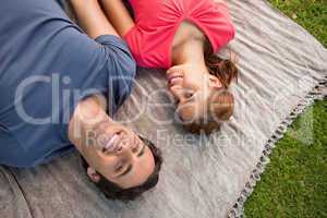 Two friends looking towards the sky while lying on a quilt
