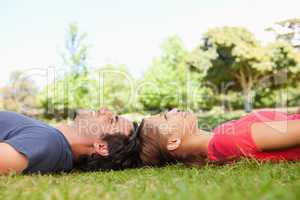 Two smiling friends looking upwards while lying head to head