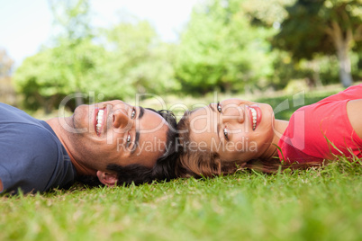 Two smiling friends looking towards the side while lying head to