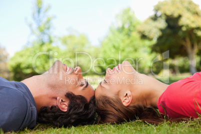 Two smiling friends with their eyes closed while lying head to h