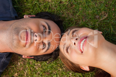 Close-up of two friends looking at each other while lying head t