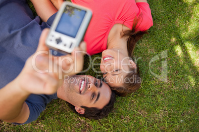 Two friends using a camera while lying side by side