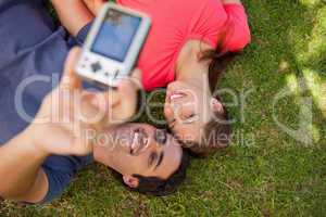 Two friends using a camera while lying side by side