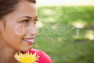 Woman looking towards the side while holding a yellow flower