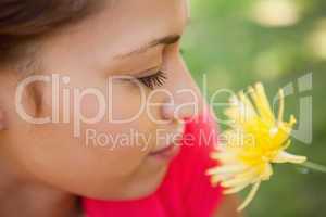 Woman closes her eyes as she smells a yellow flower