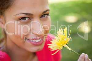 Woman smiling as she looks upwards while holding a yellow flower