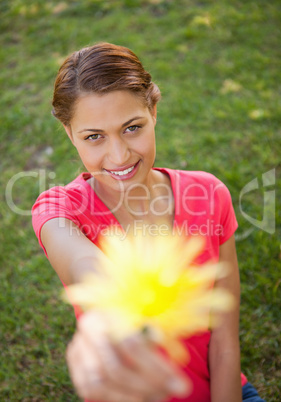 Woman holding a flower in one hand at arms reach
