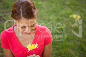 Woman looking downwards at a yellow flower