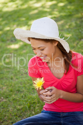 Woman laughing while wearing a white hat and holding a yellow fl