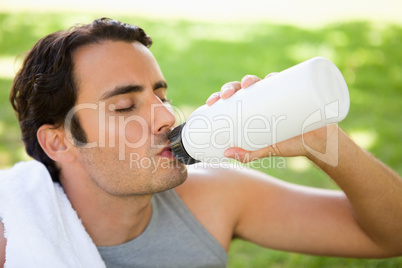 Man drinking from a sports bottle with his eyes closed