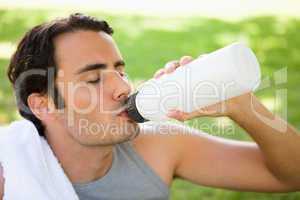 Man drinking from a sports bottle with his eyes closed
