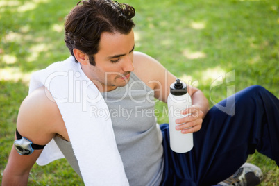 Man with a towel on his shoulder looking at a sports bottle