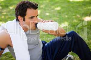 Man looking ahead while drinking from a sports bottle