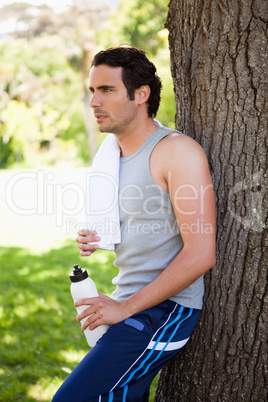 Man with a towel on his shoulder, holding a sports bottle while
