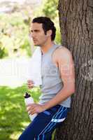Man with a towel on his shoulder, holding a sports bottle while