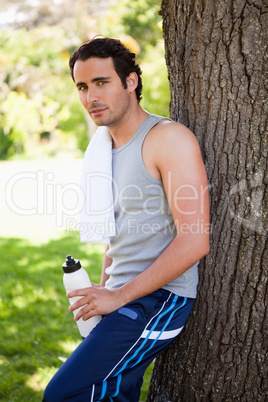 Man looking to the side while holding a sports bottle and restin