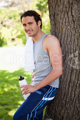 Smiling man looking to the side while holding a sports bottle an