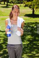 Woman smiling while holding a sports bottle and a towel