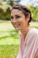 Woman looking into the distance while sitting on the grass