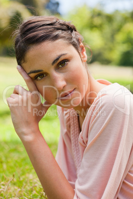 Woman tilting her head against her fingers while lying on her fr