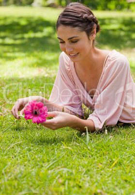 Woman lying on her front while holding a flower