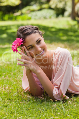 Woman lying on her front while holding a flower against her head