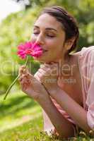 Woman smelling a flower while lying on her front