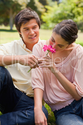 Woman smelling a flower which is being given to her by a man
