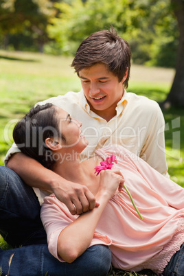 Woman holding a flower while lying against her friend who is loo