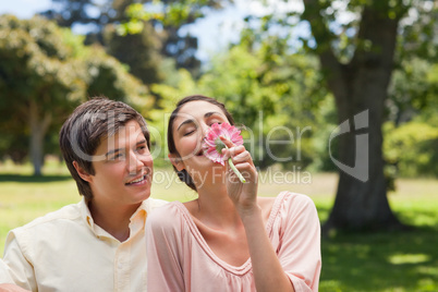 Man watching his friend while she is smelling a flower