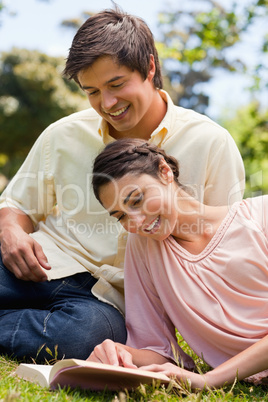 Two friends reading a book while lying down together