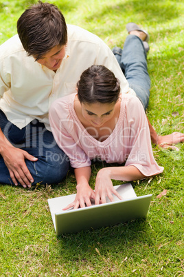 Two friends looking into a laptop together while lying down