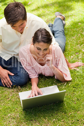 Woman resting her face against her hand while using a laptop wit