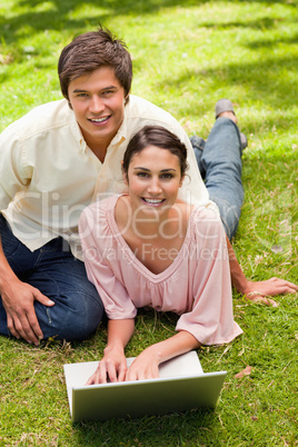 Two friends looking ahead while using a laptop